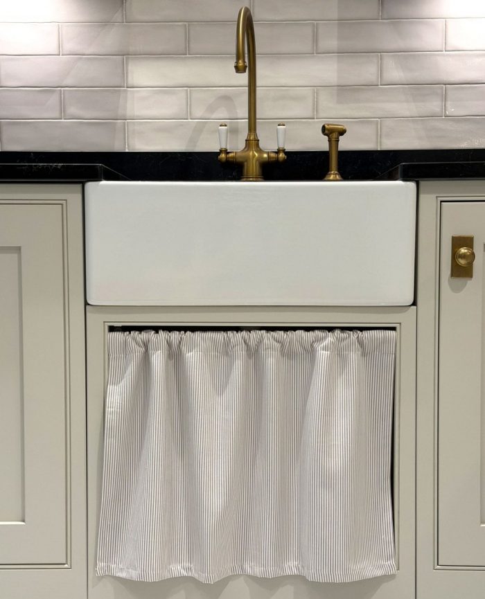Pinstripe linen cafe curtain in a kitchen underneath a sink