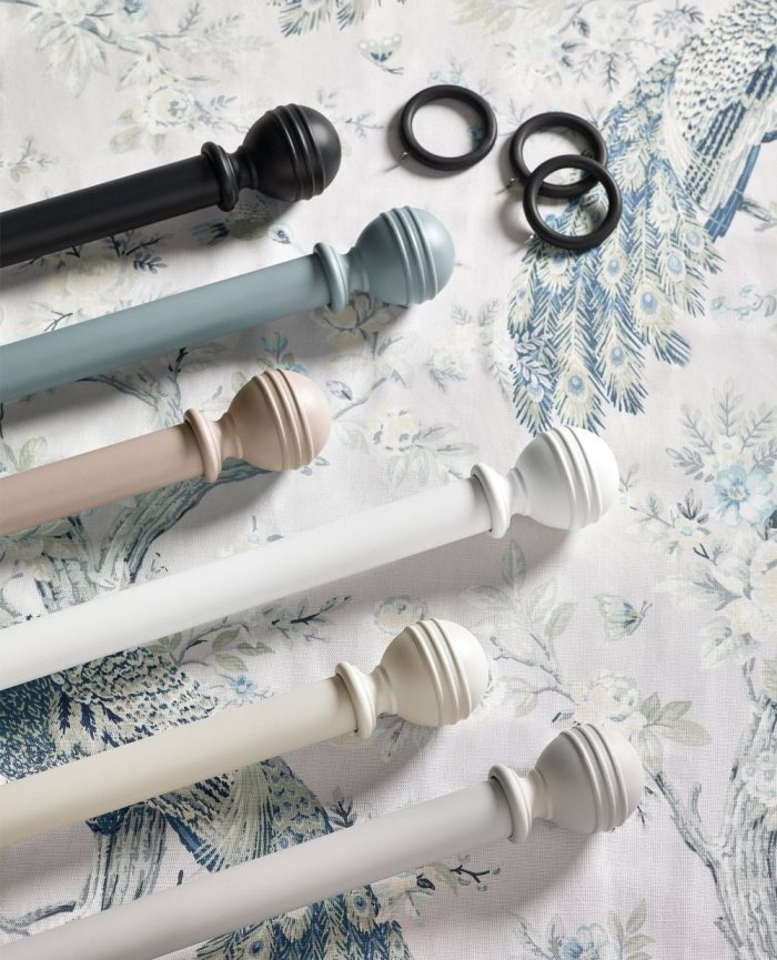 Colourful curtain poles lying on a patterned surface with some black curtain rings