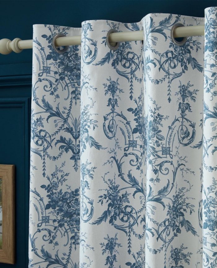 White and blue pattern eyelet curtains hanging on a white wooden pole