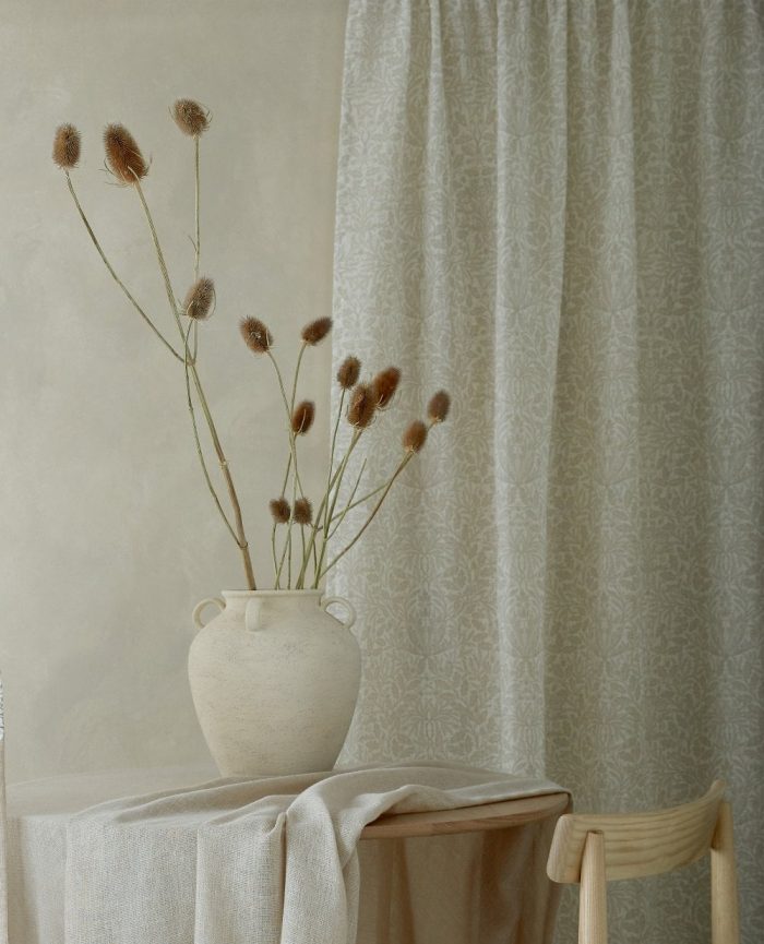 White and natural coloured printed curtains with a table and chair next to them