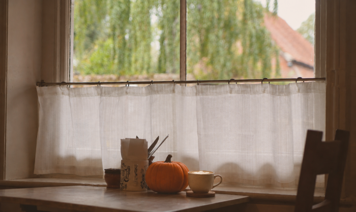 White linen cafe curtain in an autumnal cafe with a pumpkin and latte on the table